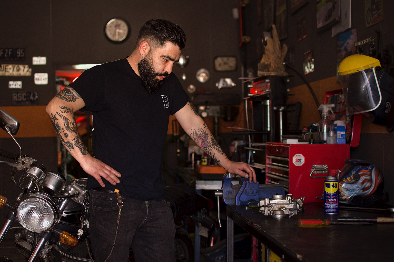 Hombre en taller mecánico junto a una Yamaha SRX y mesa de trabajo